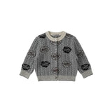 A gray cable-knit cardigan sweater with black embroidered floral and circular patterns, featuring a cream ribbed collar, cuffs, and hem, displayed flat against a light gray background.