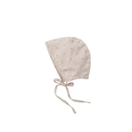 A light beige cotton bonnet with a small orange floral pattern and adjustable drawstrings, shown flat on a light gray background.