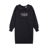 A black long-sleeve sweatshirt dress with a Peter Pan collar, featuring a white graphic print on the chest that reads 'Be the Child' with a heart and stars, shown against a plain white background.