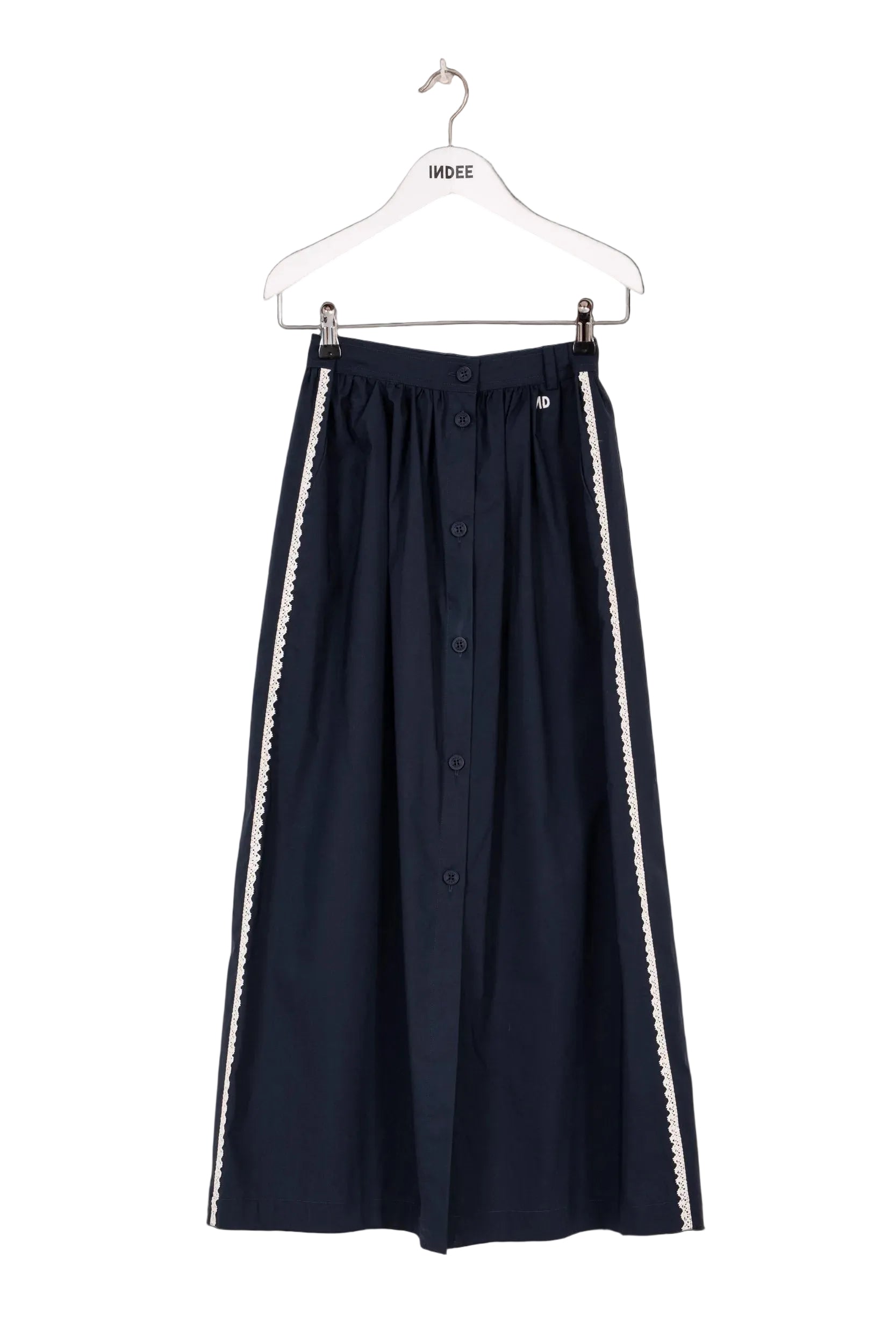 Navy skirt with white trim on a hanger against a black background